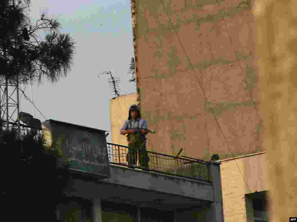 A gunman monitors the demonstrations from a rooftop.
