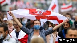 A demonstrator wearing a face mask to protect against coronavirus waves an old Belarusian national flag during an opposition rally to protest the official presidential election results in Minsk on September 27.