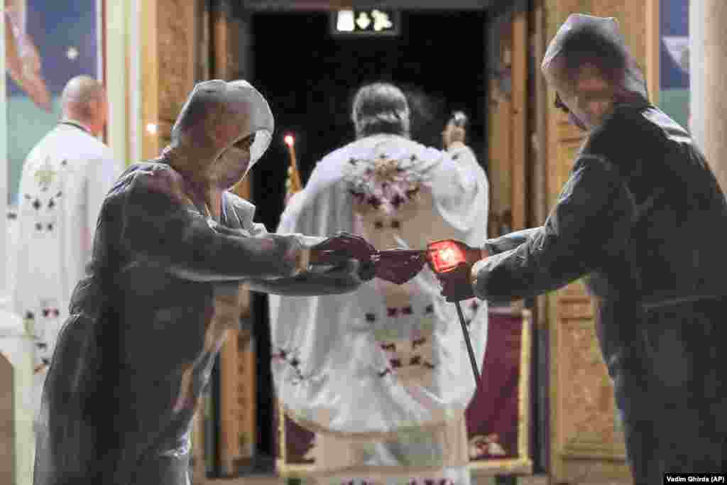 Volunteers wearing protective outfits light candles during the Orthodox Easter service in Bucharest on April 18.