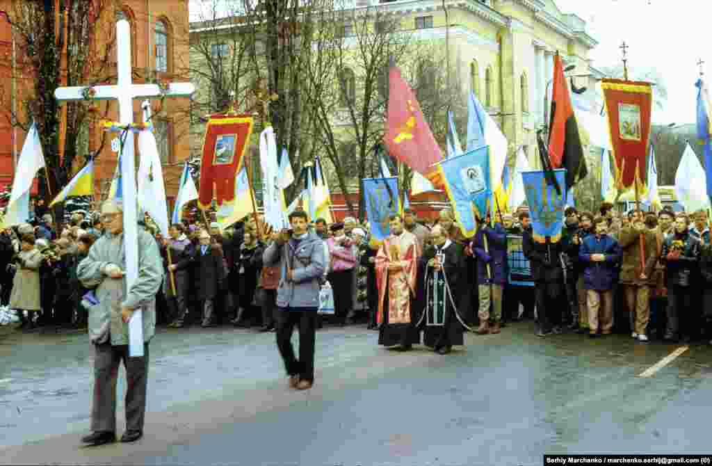Учасники церемонії перепоховання підходять до червоного корпусу Київського національного університету імені Тараса Шевченка. Несе хрест – активіст УГС Олекса Миколишин
