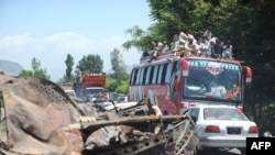 A convoy of local residents travels past wreckage as they flee the area of military operations against Taliban militants in the Naway Kalay area of Swat Valley on May 15.