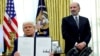 Președintele american Donald Trump arată un ordin executiv privind creșterea tarifelor, flancat de secretarul american al comerțului, Howard Lutnick, în Biroul Oval al Casei Albe din Washington, D.C., SUA, 13 februarie 2025.