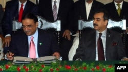 Pakistani President Asif Ali Zardari (left) signing a constitutional reform law as Prime Minister Yousuf Raza Gilani (R) looks on during a ceremony in Islamabad in April 2010.
