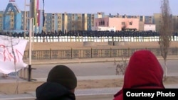 Locals watch in January as security forces occupy the square in Zhanaozen where clashes killed at least 16 people on December 16.