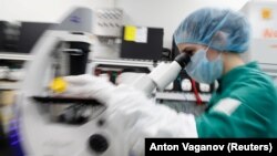 A scientist examines COVID-19 infected cells under a microscope during research for a vaccine at a laboratory of BIOCAD biotechnology company in St. Petersburg, Russia, on May 20.