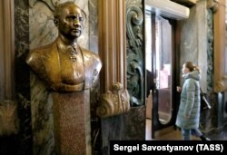 A woman enters Yeliseyevsky past a bust of its founder on April 11, the shop's last day of business.