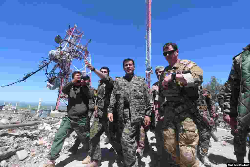 A U.S. military commander (right) with YPG fighters as they inspect the damage done to a YPG base after it was hit by Turkish air strikes. 