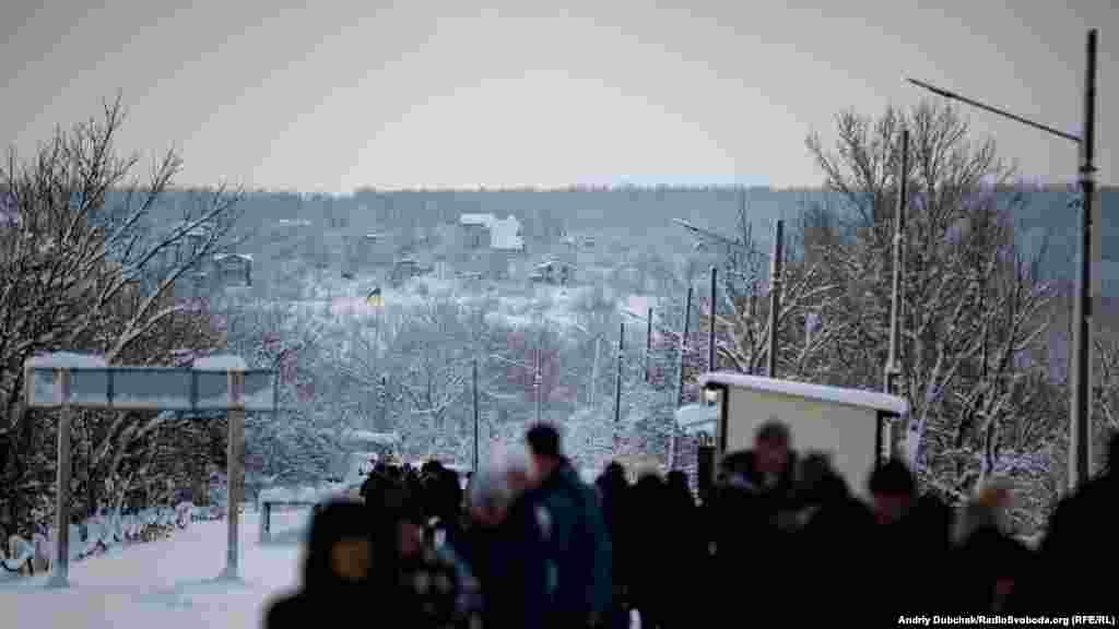 A last Ukrainian flag marks the edge of territory safe for RFE/RL's correspondents. In the empty houses on the hill, snipers often set up after the "border" closes at 5 p.m. A Ukrainian soldier was wounded by a sniper firing from this hill around one week before RFE/RL visited. 