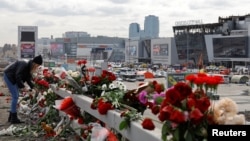 O femeie depune flori pe marginea drumului, în fața primăriei sălii de concerte Crocus City Hall, în urma unui atac terorist care a provocat moartea a 140 de persoane.