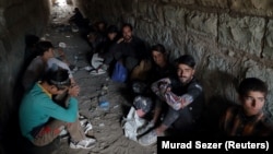 Afghan migrants hide from security forces in a tunnel under train tracks after crossing illegally into Turkey from Iran on August 23, 2021 -- days after the Taliban seized power in Afghanistan.