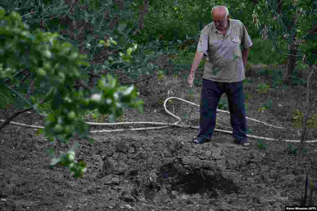 Čovjek pokazuje na krater od granate u armenskom selu Aygepar 15. jula.