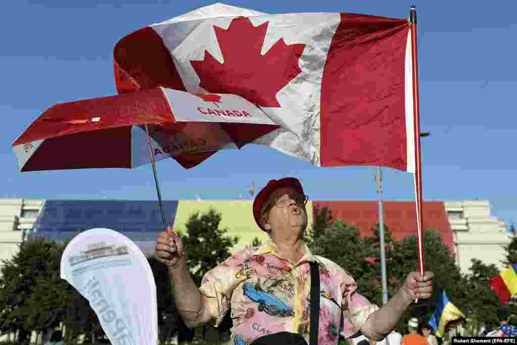 A protester waves a Canadian flag on August 12, as a third night of protests began. The protests have been dubbed the "diaspora protests" due to the number of Romanians who traveled home from abroad to take part in the demonstrations.