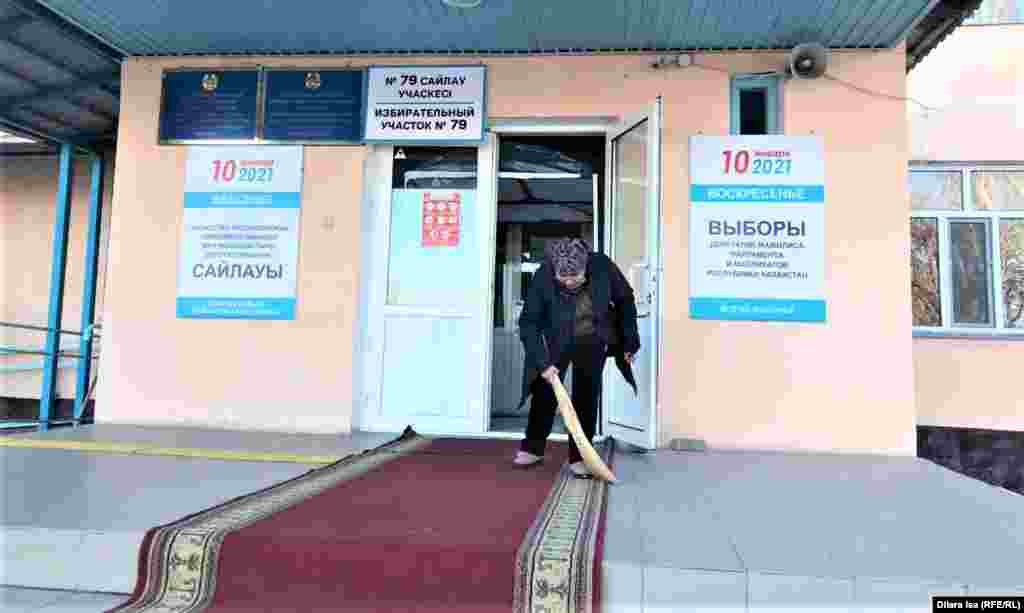 A woman sweeps up outside polling station No. 79 in Shymkent.