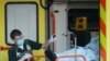 Bolničar iznosi pacijenta iz ambulantnih kola u Velikoj Britaniji