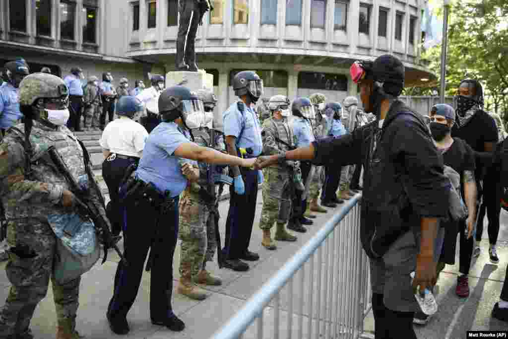 Prosvjednik i pripadnik policije izvode "pozdrav pesnicama" ispred policijske postaje u Philadelphiji, 1. lipnja.