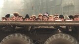 Grup de tineri revoluționari români în spatele unui vehicul al Armatei.