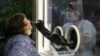 Russia -- A staff member of AltraVita fertility clinic takes a swab from an outdoor booth as a woman undergoes a test for the coronavirus disease (COVID-19) in Moscow, June 11, 2020