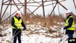 Latvian Energy Minister Kaspars Melnis (left) and Rolands Irklis, the CEO of Latvian electricity operator AST, pose with a severed cable after technicians worked on the disconnection of a major power line between Latvia and Russia on February 8.