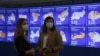 Two women stand near a digital board displaying preliminary results in Russia's regions of the nationwide referendum in July 2020. Critics fear the new system's lack of transparency and voter-verification safeguards could open the way for vote manipulation.