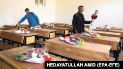 School workers place donated bouquets of flowers on the empty desks of students killed in a May 8 attack on the Sayed al-Shuhada school in Kabul's Hazara district.
