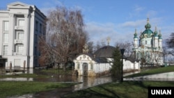 На передньому плані так звана «каплиця» УПЦ (Московського патріархату), незаконно збудована біля фундаменту Десятинної церкви на території Національного музею історії України. Зараз суд ухвалив рішення про її знесення