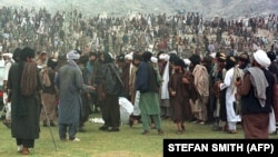 دا انځور د ۱۹۹۸ز کال دی چې پکې طالبان په کابل کې په یوه لوبغالي کې یو کس ته د غلا په تور تر سزا ورکولو وروسته ولاړ دي.