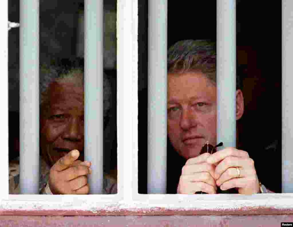 U.S. President Bill Clinton (right) and Nelson Mandela peer through the bars of the cell in which Mandela spent 17 years on Robben Island in March 1998.