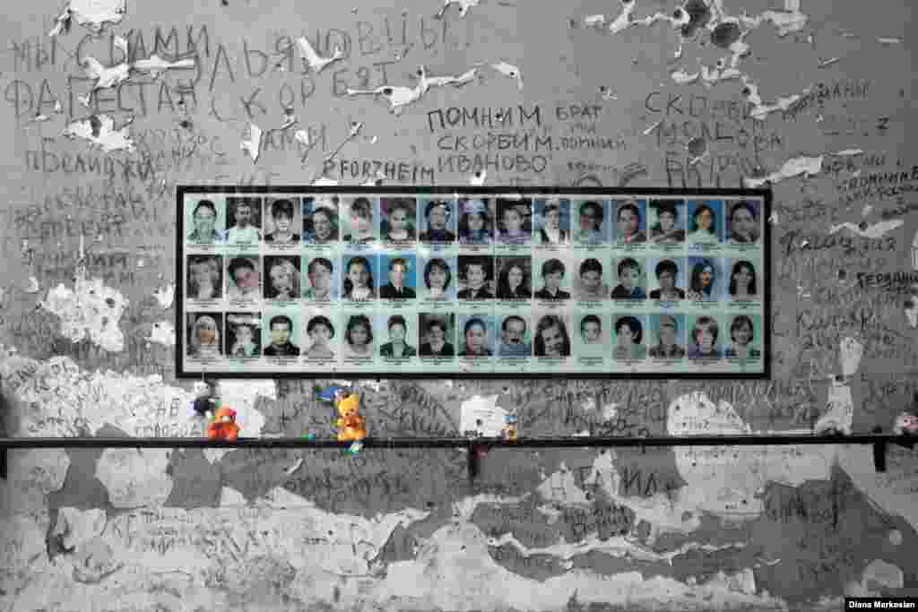 At School No. 1, portraits of more than 300 victims hang in the gymnasium where 1,100 children, parents, and teachers were held hostage for 52 hours. The school stands in ruins, and the room itself has been largely untouched since 2004. Bullet holes and haunting inscriptions of "we remember" adorn the walls; there is a charred gym ladder to one side and blackened basketball hoops at either end. An Orthodox cross has been placed in the middle of the gym floor, surrounded by freshly opened bottles of water left to commemorate the captives, who endured over two days in fierce summer heat with almost no water. Residents continue to bring teddy bears, model cars, and other toys in memory of the 186 children who were killed here. 