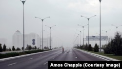A street cleaner on one of the massive, mostly empty highways running out of Ashgabat as a rainstorm sweeps into the city.