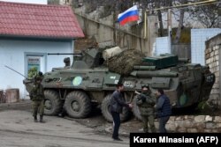Men interact with a Russian peacekeeper in the town of Lachin on November 30, 2020.