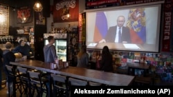 Staff and customers of a Moscow bar watch Russian President Vladimir Putin address the nation on state television on March 25. 