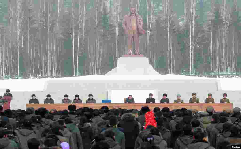 Северокорейские чиновники слушают Ким Чен Ына во время церемонии открытия. За трибуной – статуя Ким Чен Ира, покойного отца Ким Чен Ына, в прошлом лидера страны, провозгласившей курс на построение коммунизма.