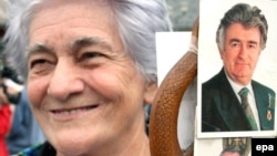 A woman holding pictures of Karadzic (top) and his army commander Ratko Mladic in the Bosnian Serb town of Pale, where hundreds gathered to pray for Karadzic on July 26