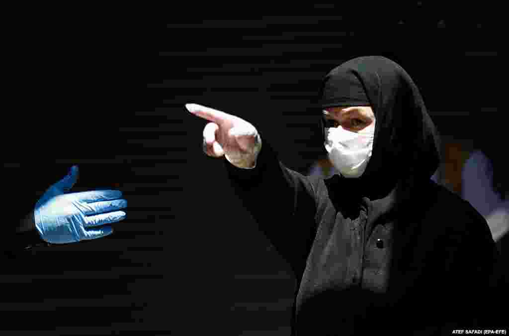 A Greek Orthodox nun, wearing a protective face mask and gloves, gestures while on her way to the Holy Fire ceremony in the church of the Holy Sepulchre, in Jerusalem's old city on April 18. Eastern Orthodox Christians believe that the Holy Fire emanates from within the Tomb of Christ. Measures were taken by the Israeli government to limit the number of services.