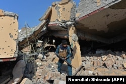 An Afghan security officer inspects a residential house that was damaged in a gunbattle between security forces and IS-K group fighters in Jalalabad in February.