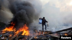 A man walks amid burning remains of barricades on Independence Square in Kyiv on February 21.
