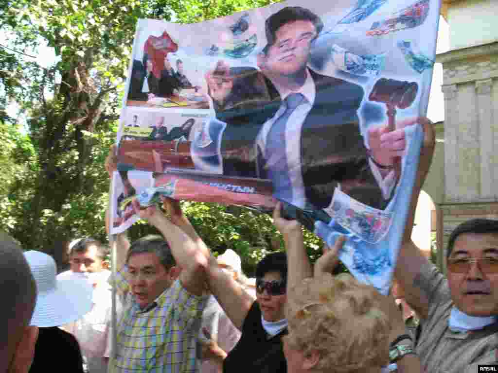 Участники акции протеста с плакатами. - Участники акции протеста в защиту СМИ держат в руках плакат с изображением депутата Ромина Мадинова, выигравшего иск в суде против газеты "Тасжарган" на сумму 30 миллионов тенге. Алматы, 24 июня 2009 года.