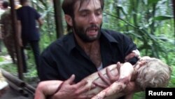 A man evacuates an injured child after Russian special forces stormed the school in Beslan in September 2004.