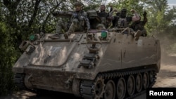 Ukrainian soldiers ride an armored personnel carrier near the frontline city of Bakhmut.