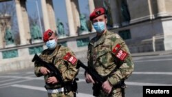 Hungarian military police officers patrol Budapest's deserted Heroes' Square during a coronavirus emergency.