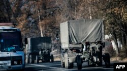 Trucks without license plates tow a 122mm howitzer artillery piece through Makiivka on November 9. 