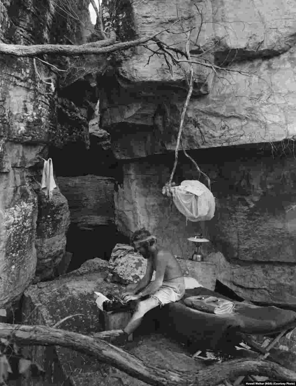 Фотокорреспондент National Geographic Гоуэлл Уокер печатает в своем "кабинете" на холме Иняларк в Австралии, на которой он провел неделю с руководителем экспедиции Арнем в 1948 году.