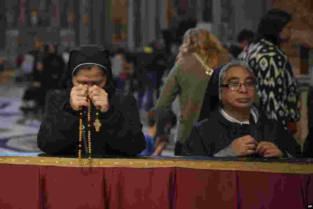 Două călugărițe se roagă în Basilica Sfântul Petru de la Vatican, acolo unde este depus sicriul cu trupul Papei Francisc.