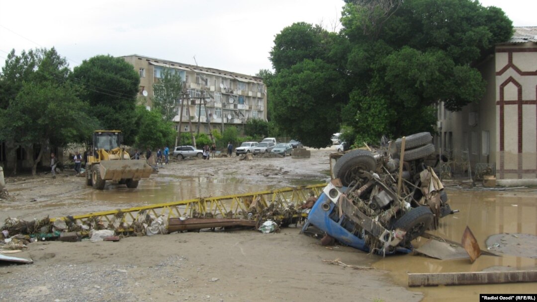 Workers clear debris after flooding in Panjakent.