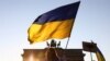Украинадагы согушка каршы Берлинде өткөн акцияда тартылган сүрөт. Акциянын катышуучусу украин желегин көтөрүп турат. Сүрөт иллюстрация үчүн колдонулду