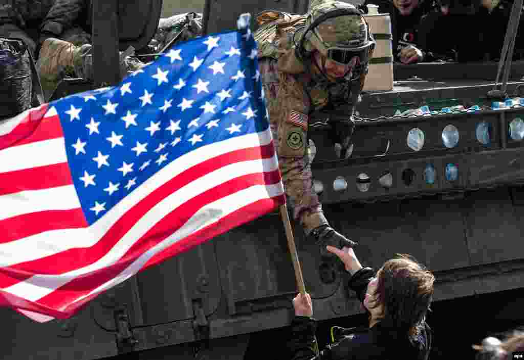 A woman waves a U.S. flag as she welcomes a soldier of the convoy known as the "Dragoon Ride."