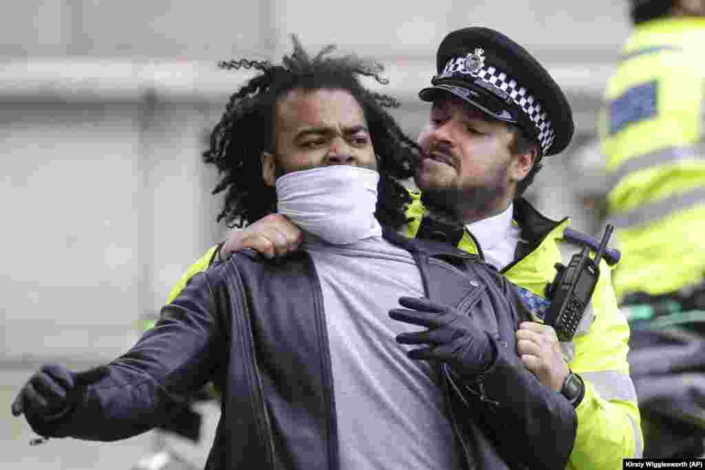 Un ofițer de poliție împiedică un protestatar să se lupte cu un trecător agresiv, în timpul unei manifestații, în Piața Parlamentului din Londra, marți, 9 iunie 2020. Adunarea a avut loc în memoria lui George Floyd.