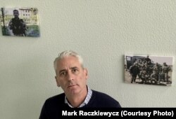 Paul Niland stands in the stairwell of Lifeline Ukraine. where pictures of Donbas war veterans hang, many of whom work as operators at the suicide-prevention call center.