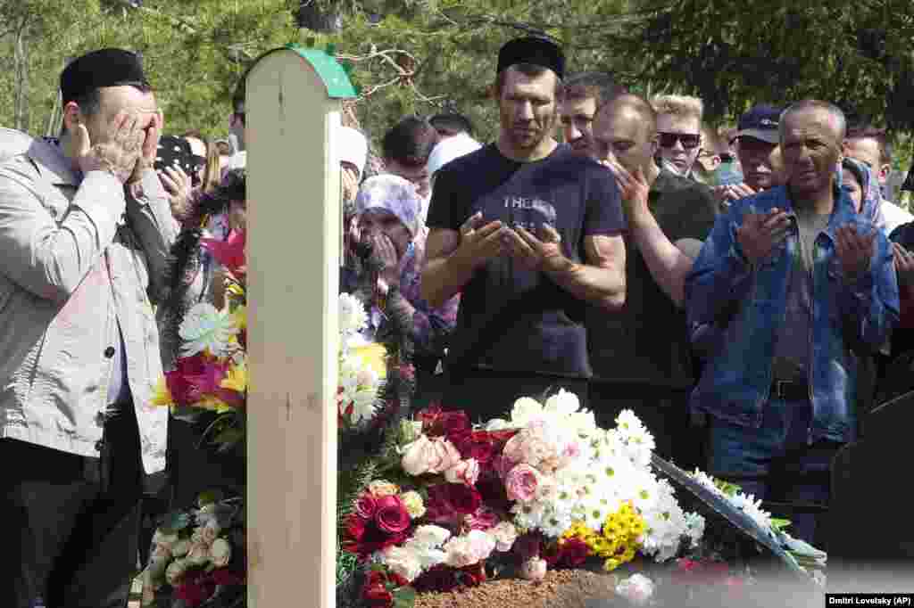 People pray next to Ignatyeva's grave.