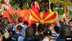Protesters hold Macedonian and Albanian flags in front of a cordon of special police guarding the government building during an antigovernment protest in Skopje last week.